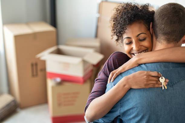 Photo of a young couple hugging while the woman holds the keys to their new house