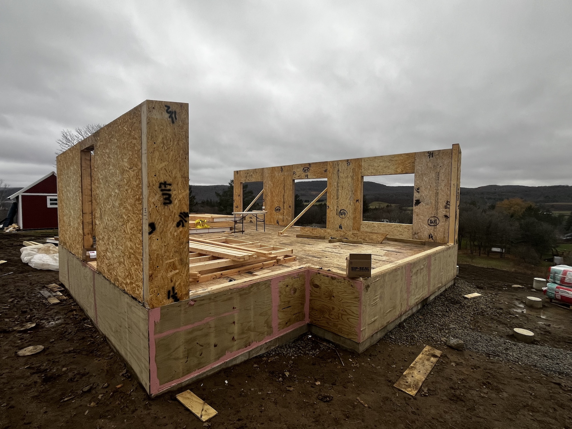 panelized cottage shell under construction in Cherry Valley, New York, showing the compact single-story structure assembled on a rural site during winter