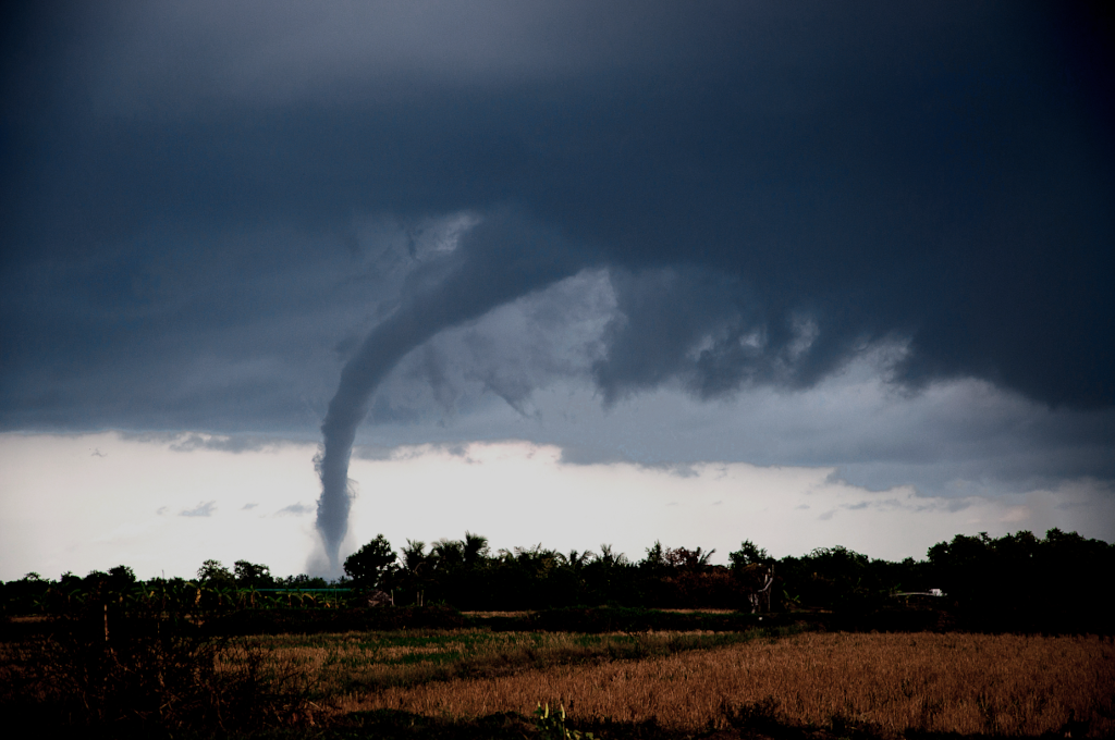 A tornado touched down in a field with dark, cloudy skies all around it