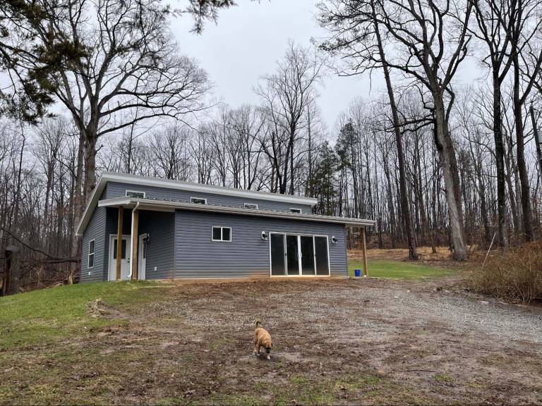contemporary SIP home on a wooded rural property, illustrating a larger small-home design that provides additional living space while remaining practical for off-grid planning, energy efficiency, and long-term full-time use
