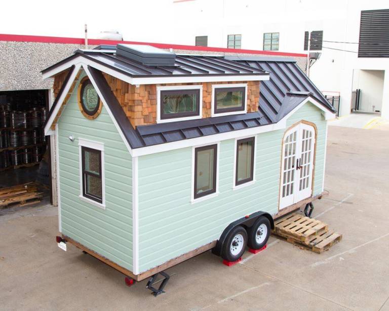 Tiny house built on a trailer with a metal roof and loft windows, illustrating The Tiny model, which can be installed on a trailer for mobility or built on a permanent foundation for long-term placement on rural property
