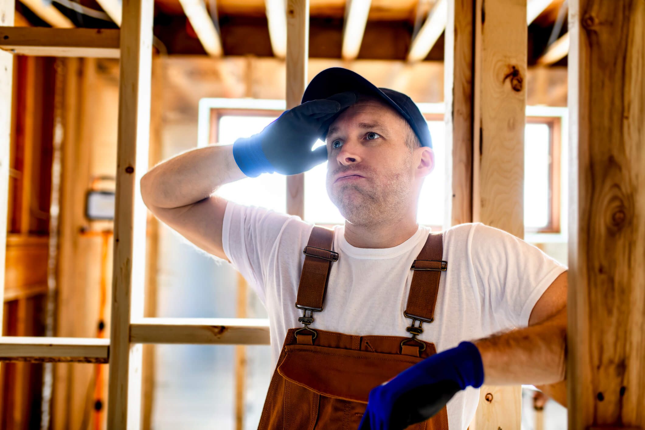 construction manager pauses inside a partially framed home, illustrating the strain on the shrinking framing workforce and the growing difficulty of keeping projects staffed.
