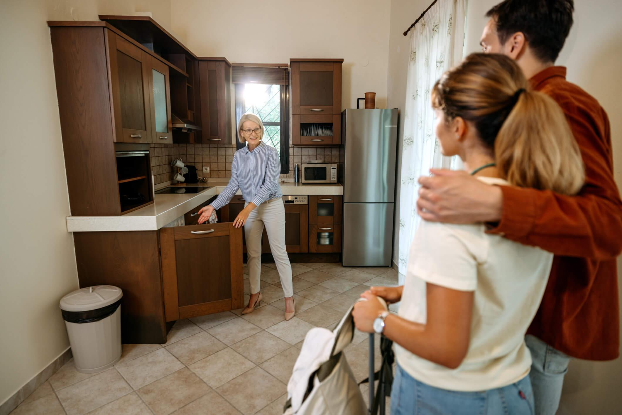 adu owner showing a kitchen to a couple during a rental walkthrough