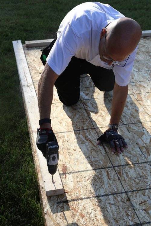 photo of a builder securing a base plate on the foundation of a small home kit