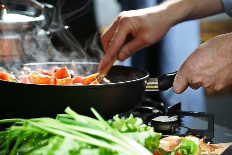 closeup photo of hands cooking food in a skillet on stove