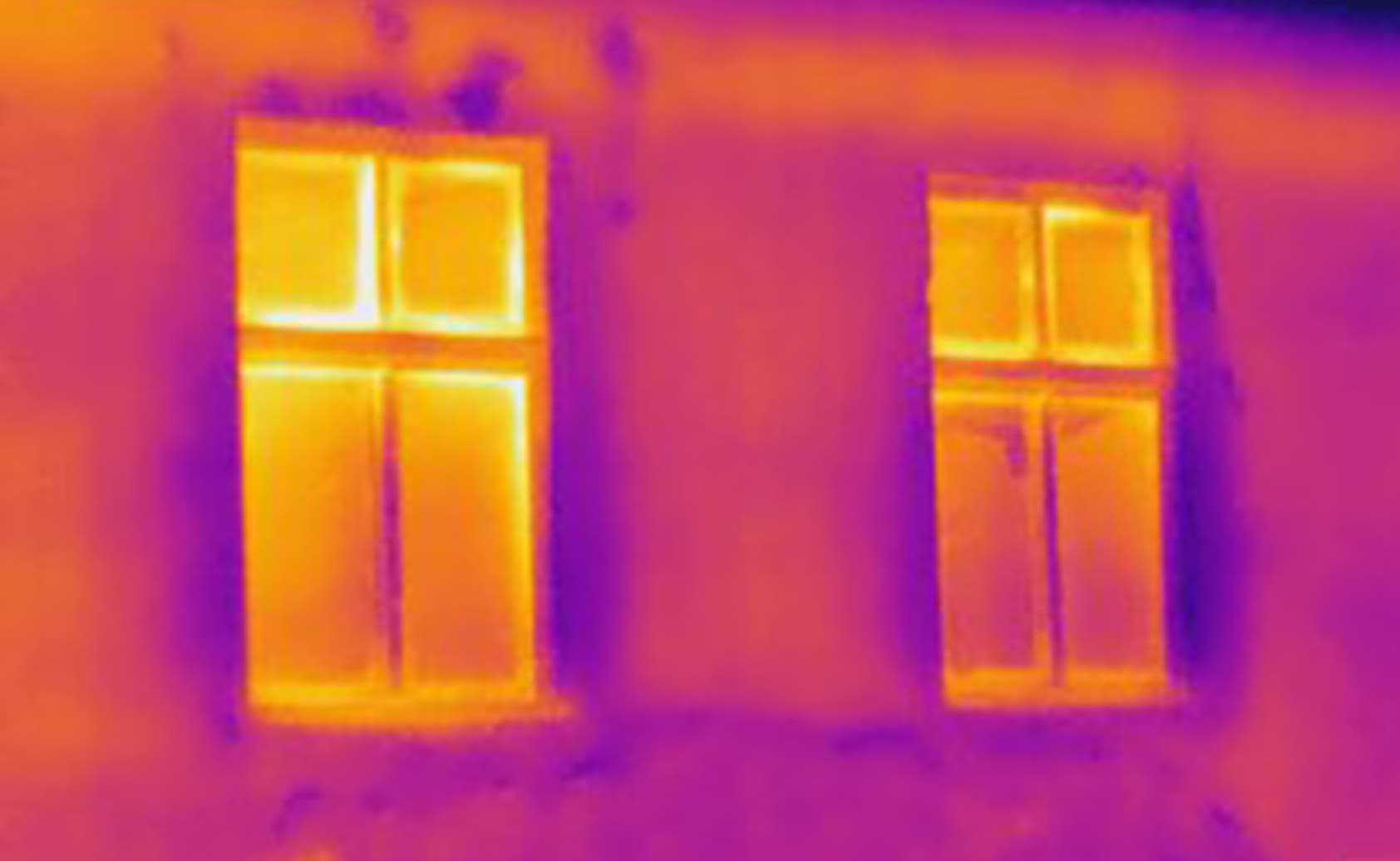thermal photo of a wall showing heat loss through framing and windows, illustrating why thermal bridging lowers whole‑wall insulation values and why SIP construction is more efficient