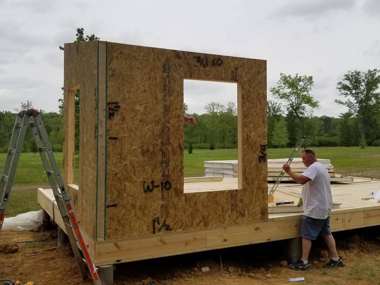 A worker checking the plumb of a wall panel with a level