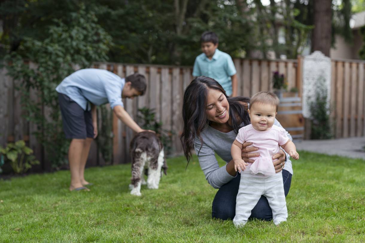 Young family with baby and dog in backyard