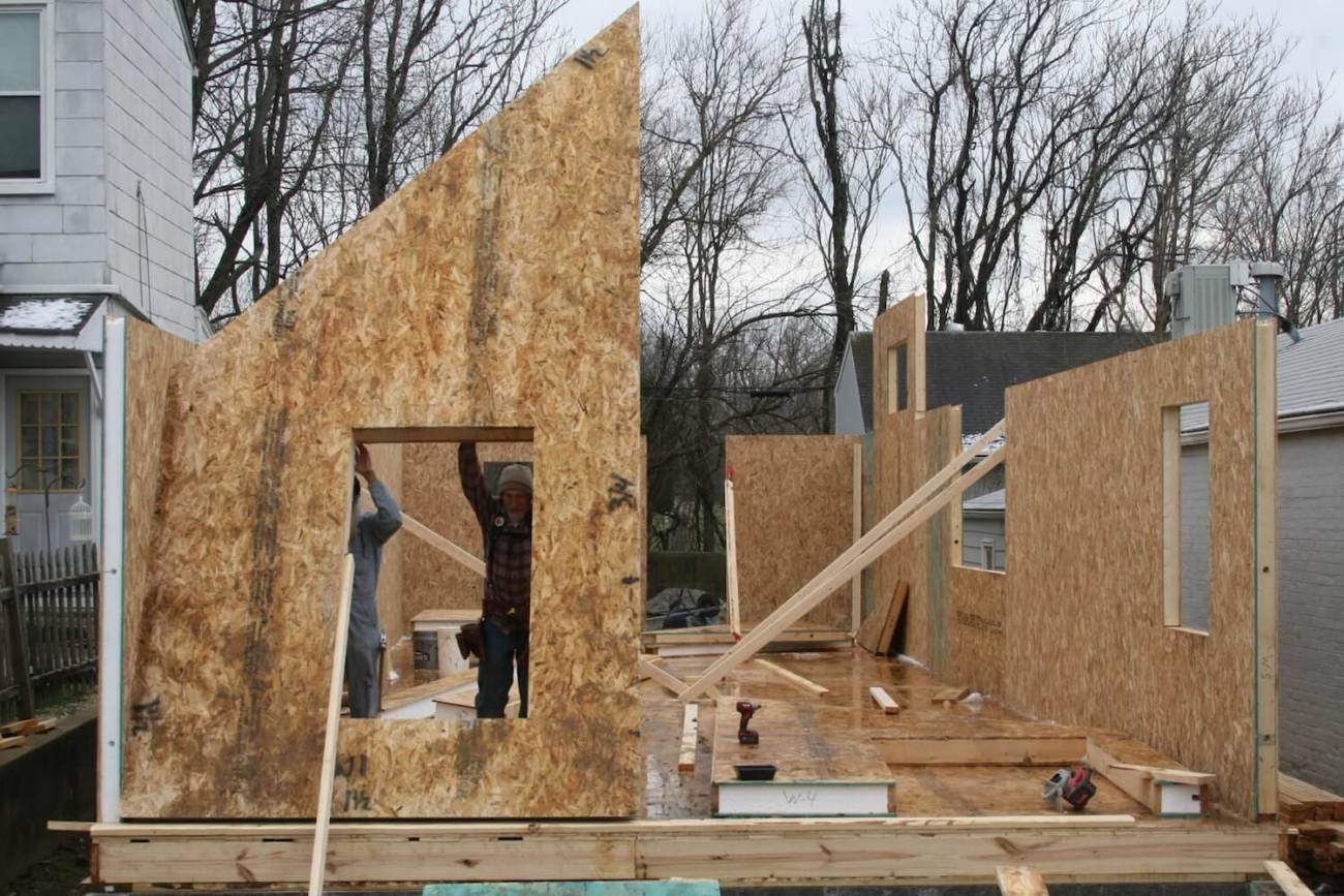 Photo of workers setting a front wall panel of a Cottage home