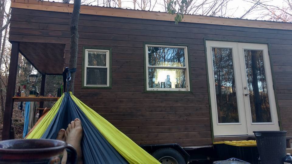 Photo showing the feet of someone in a hammock relaxing outside their tiny home