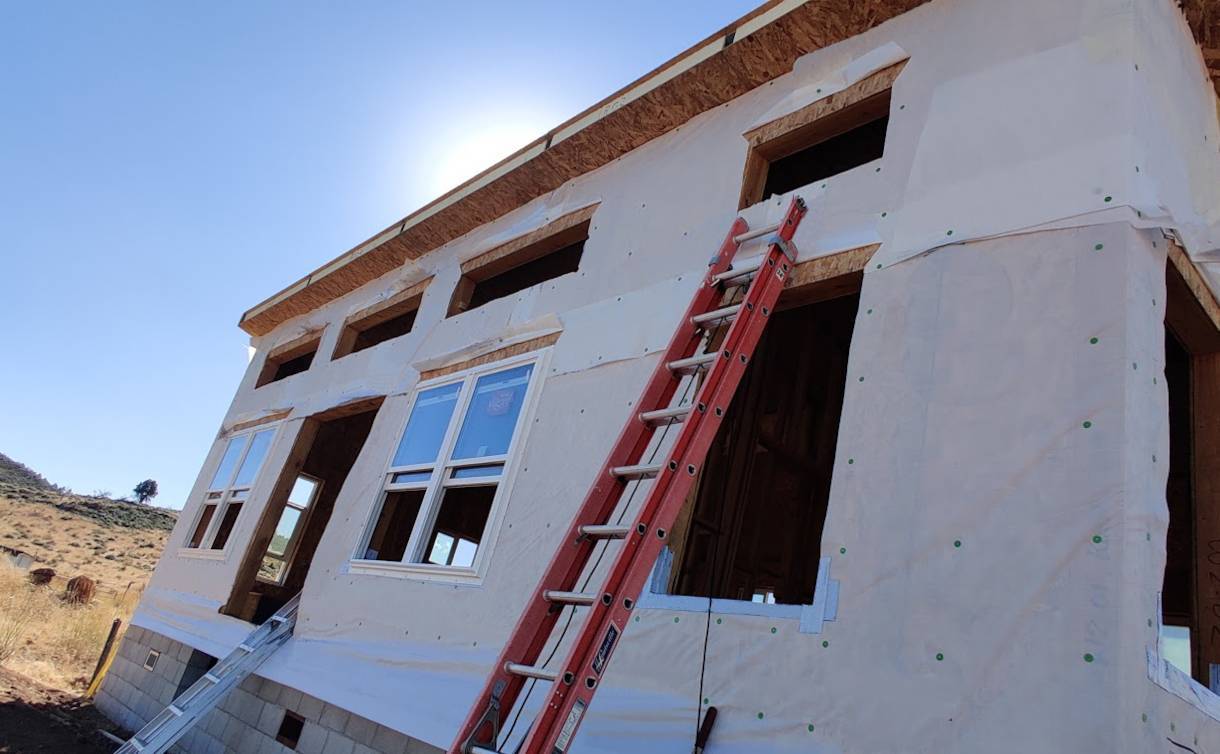 Image of ladders leaning against the house after house wrap installation
