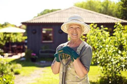 Photo of a retired lady pausing for a picture while gardening