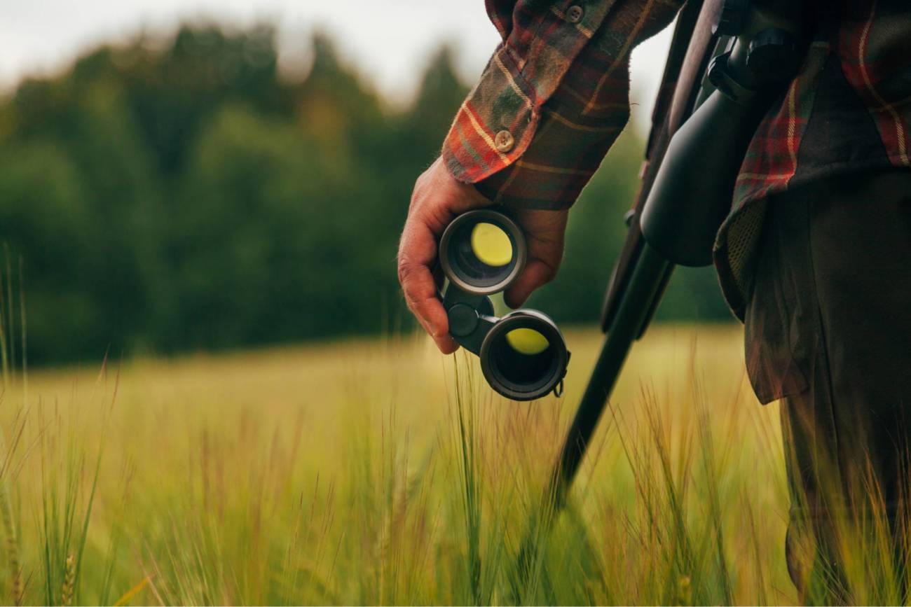 Close-up photo of a hunter's hand holding binoculars