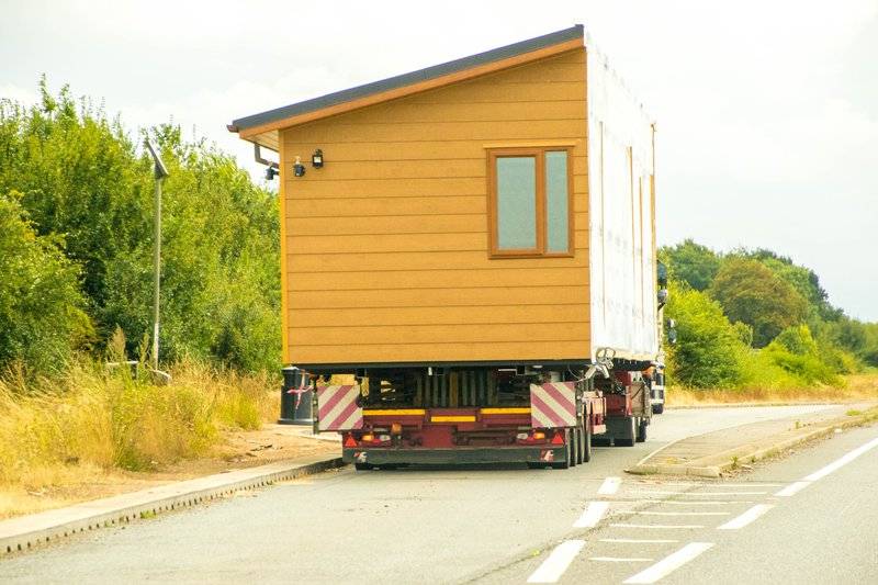 a manufactured home being transported by a truck on the highway