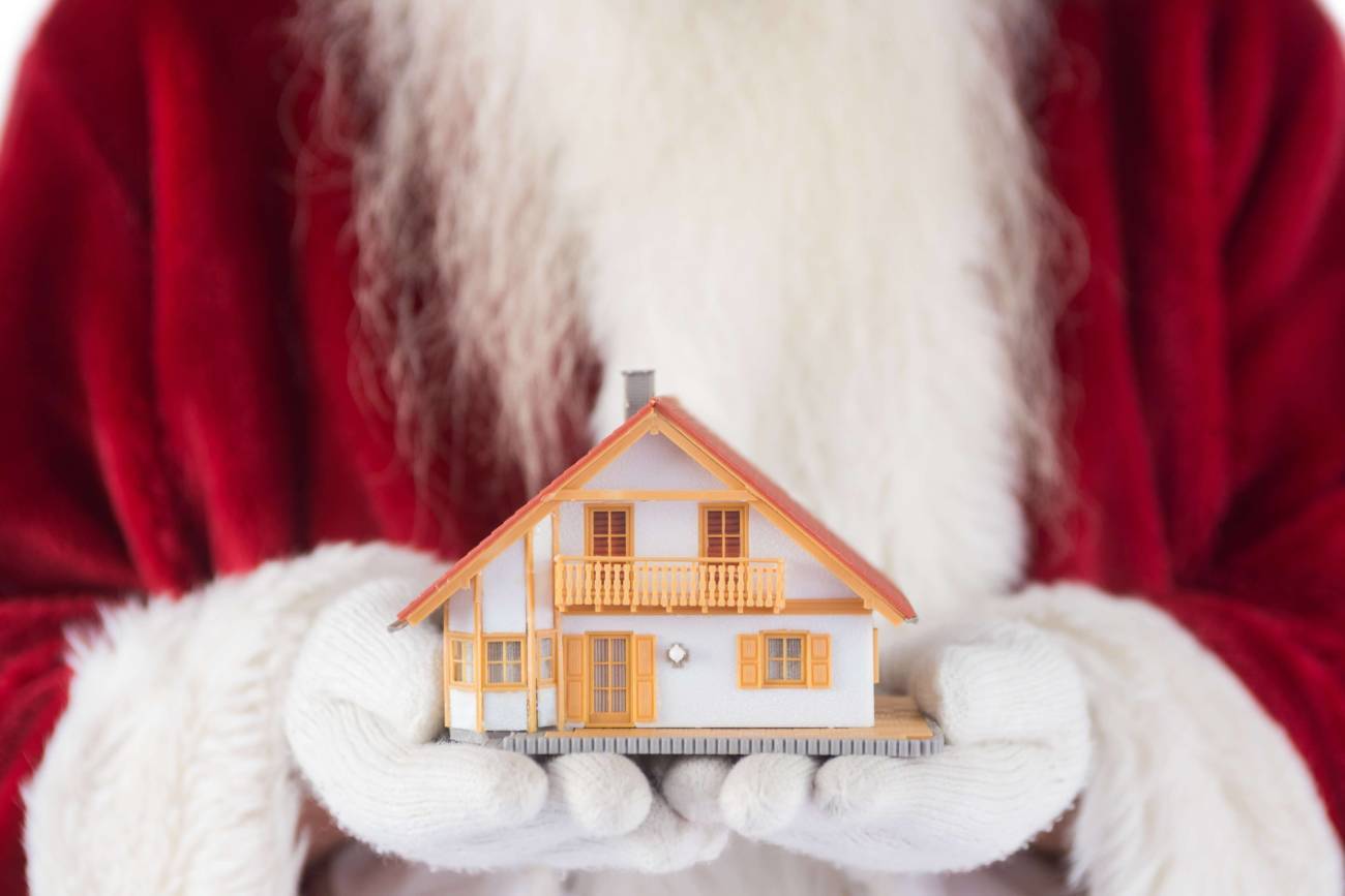 Close-up photo of Santa Claus with a small home in his hands